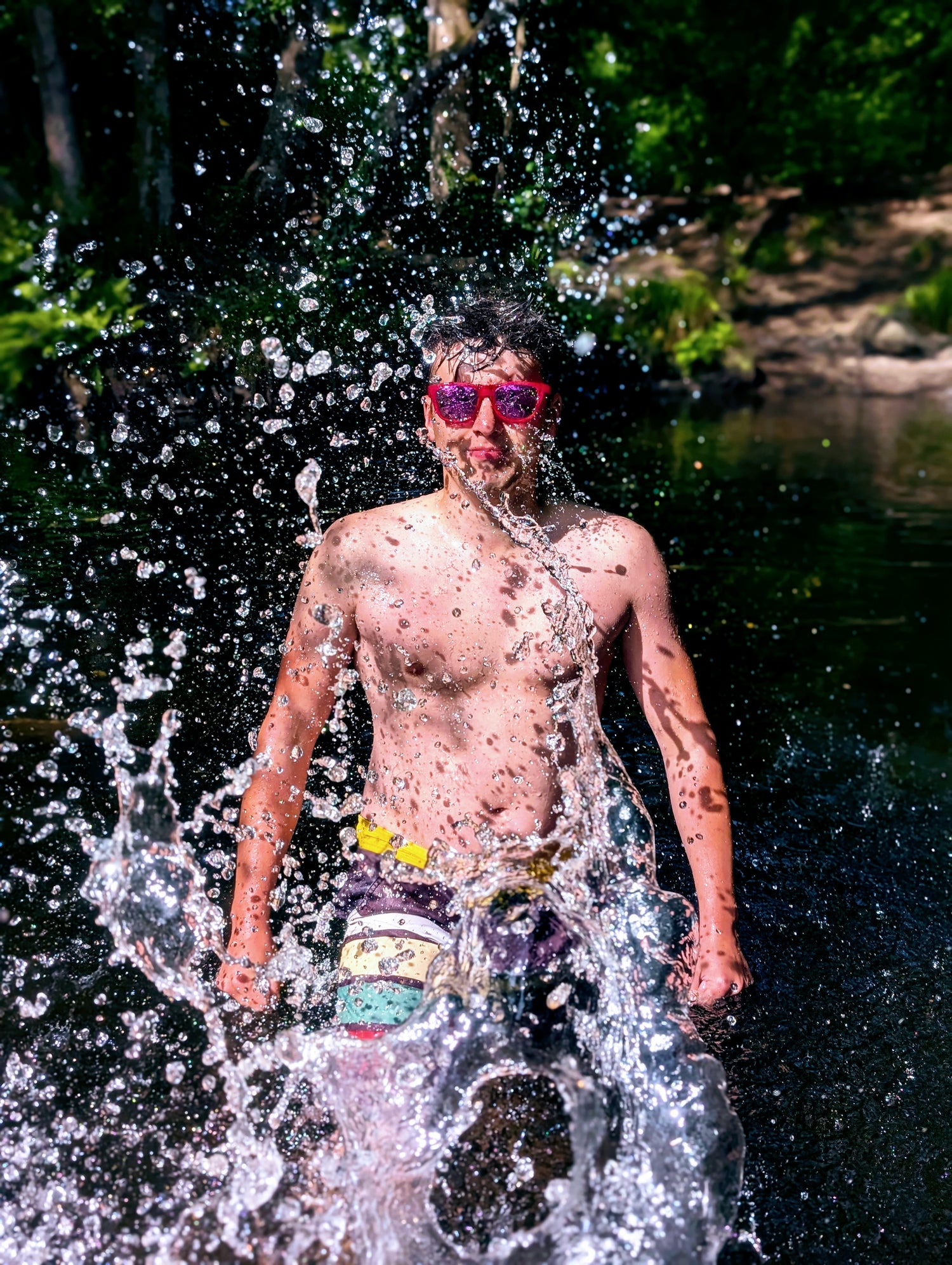 man being splashed by water wearing bright pink sunglasses