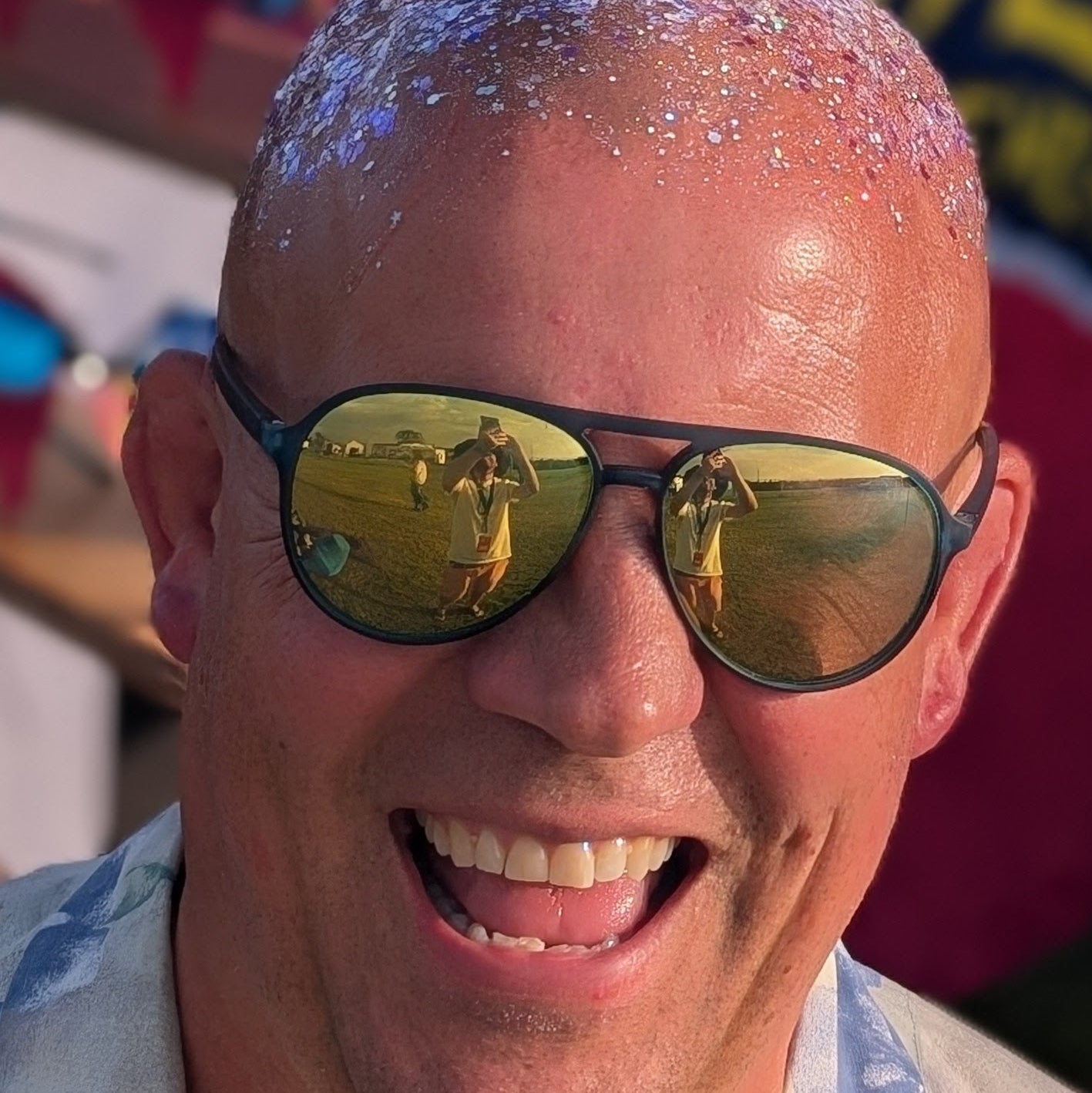 Man laughing wearing sunglasses and glitter on his head