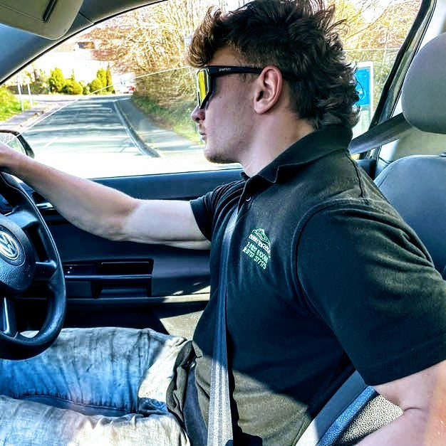 Man wearing sunglasses driving a car in old clothes